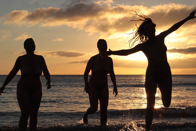 <p>Nudists take part in the annual North East Skinny Dip as the sun rises at Druridge Bay in Northumberland</p>