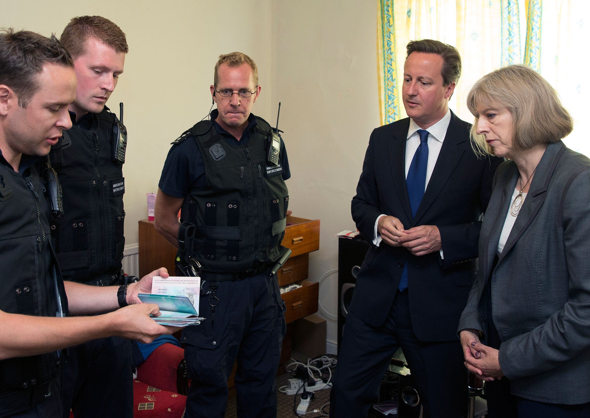 David Cameron and Theresa Mayspeak to Immigration Enforcement officers at a property where six immigrants were arrested on July 29, 2014 in Slough, England.
