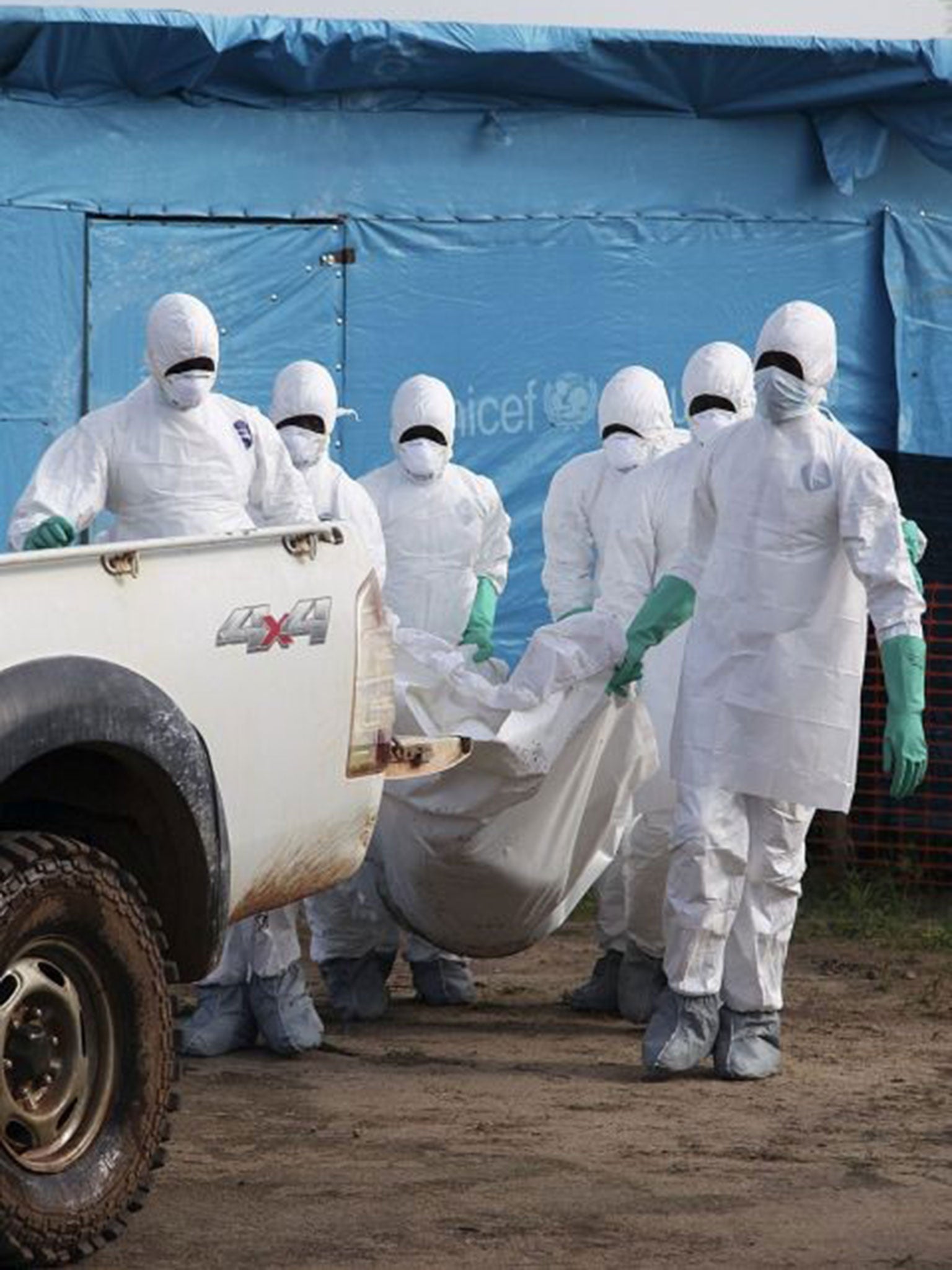 Liberian health workers in protective gear on the way to bury a woman who died of the Ebola virus (EPA)