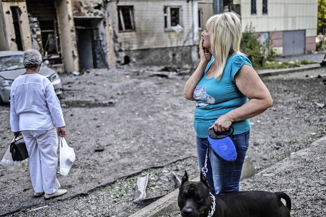 People look at a damaged area after shelling in Donetsk