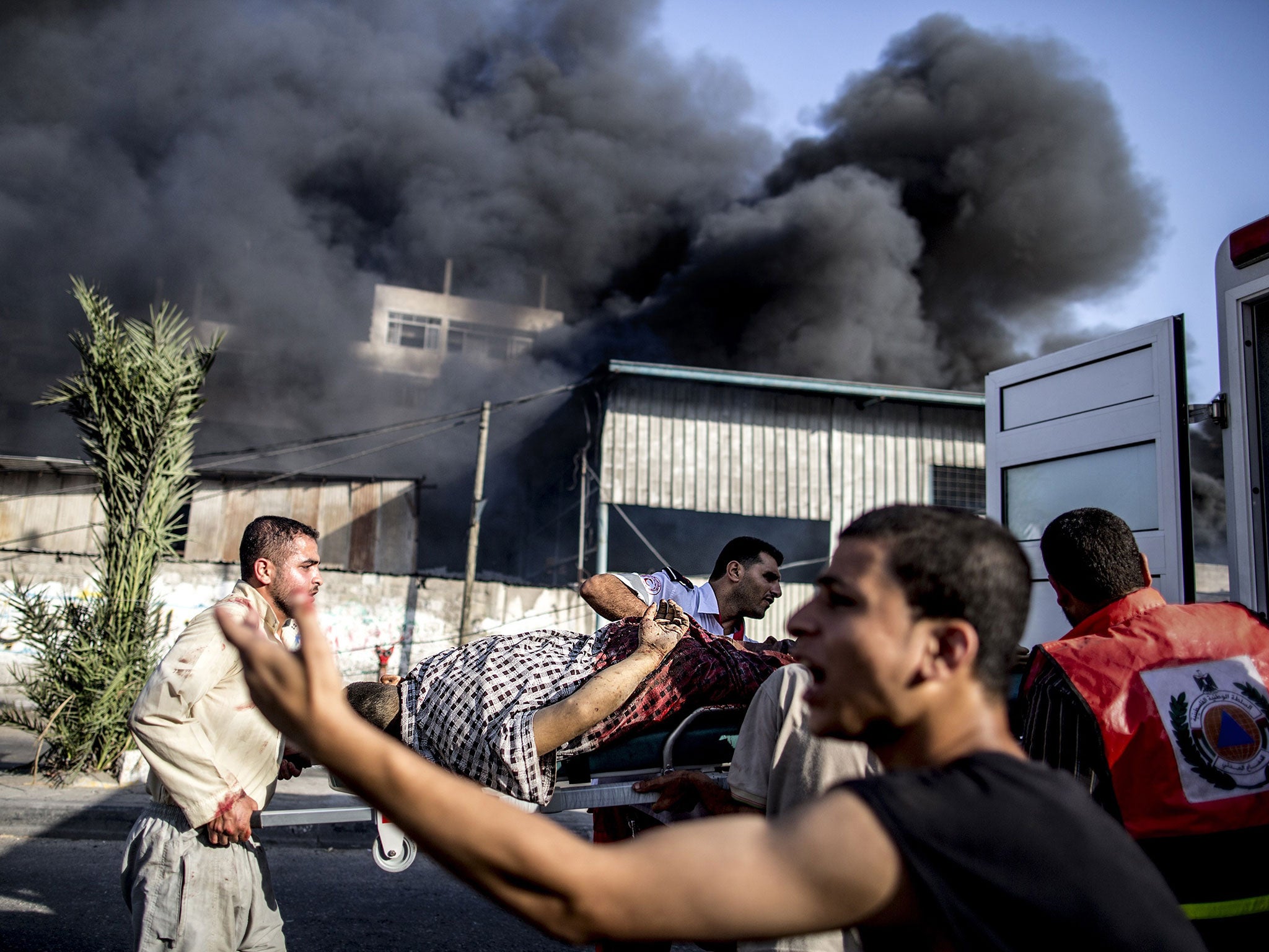Palestinian emergency personnel evacuate a wounded man following an Israeli air strike on a market place in the Shejaiya neighbourhood near Gaza City