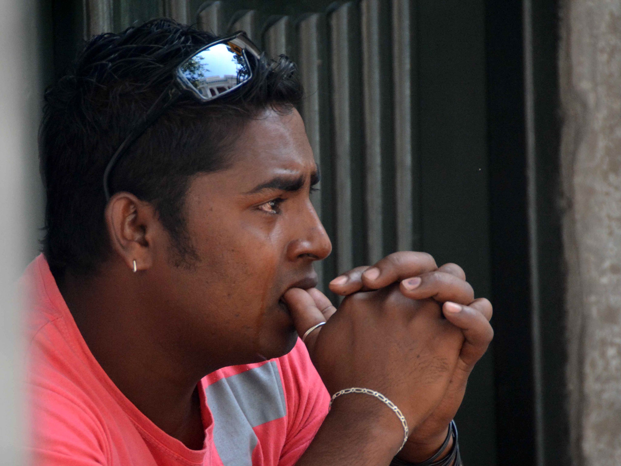 An immigrant who works in Greece cries outside a court in the southwest city of Patras, Greece, on Wednesday, July 30, 2014