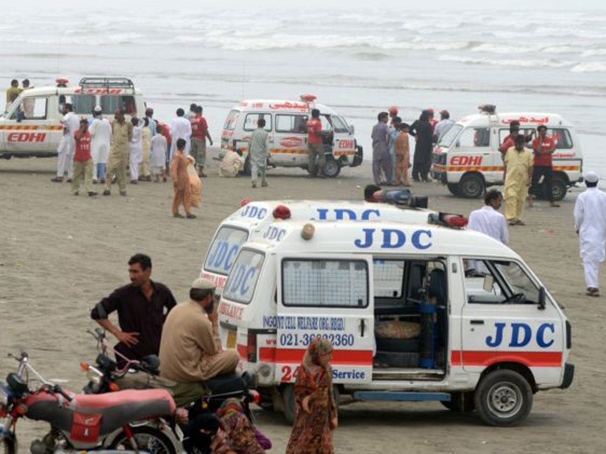 Ambulances are pictured at the beachfront during recovery operations in search of missing bathers at Clifton beach in Karachi