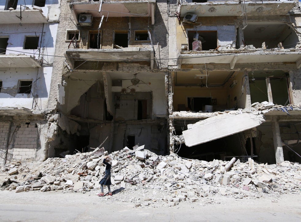 A girl carries bread as she walks past a damaged building in Aleppo 
