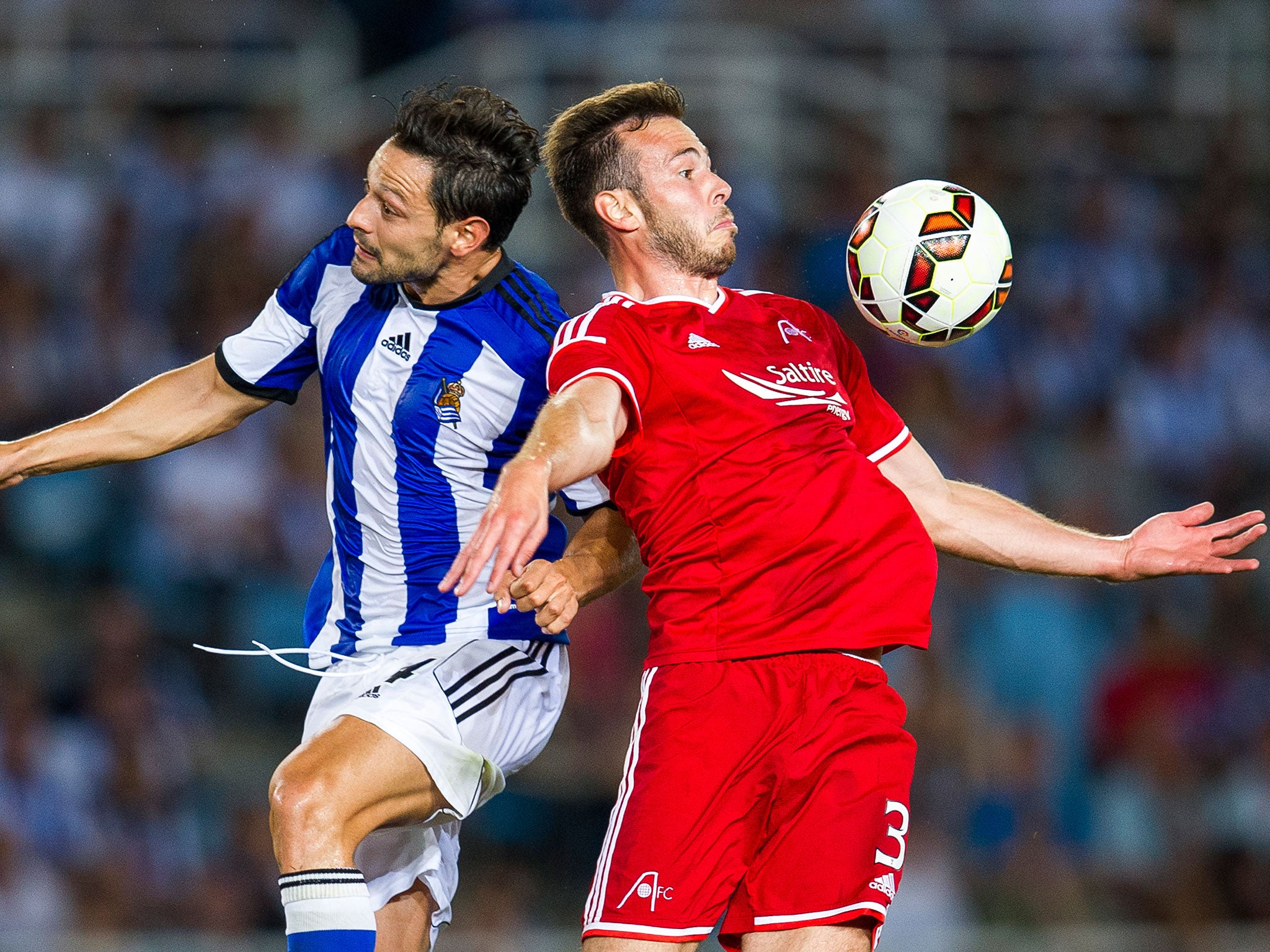 Andrew Considine of Aberdeen CF duels for the ball with Alberto de la Bella of Real Sociedad