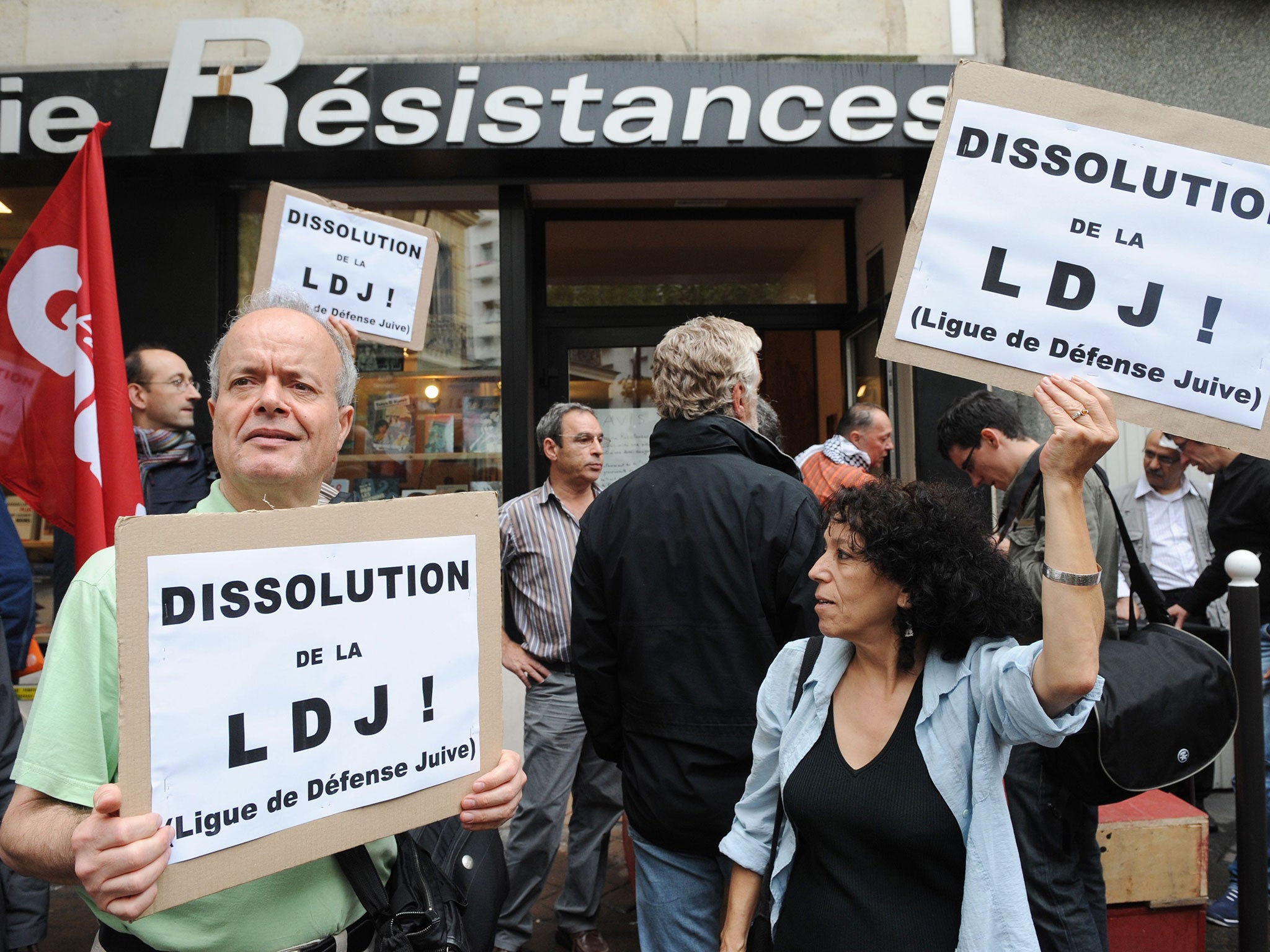 People hold signs reading "Dissolution of the LDJ!" during a demonstration calling for the ban of the Jewish Defense League (Ligue de Defense Juive)