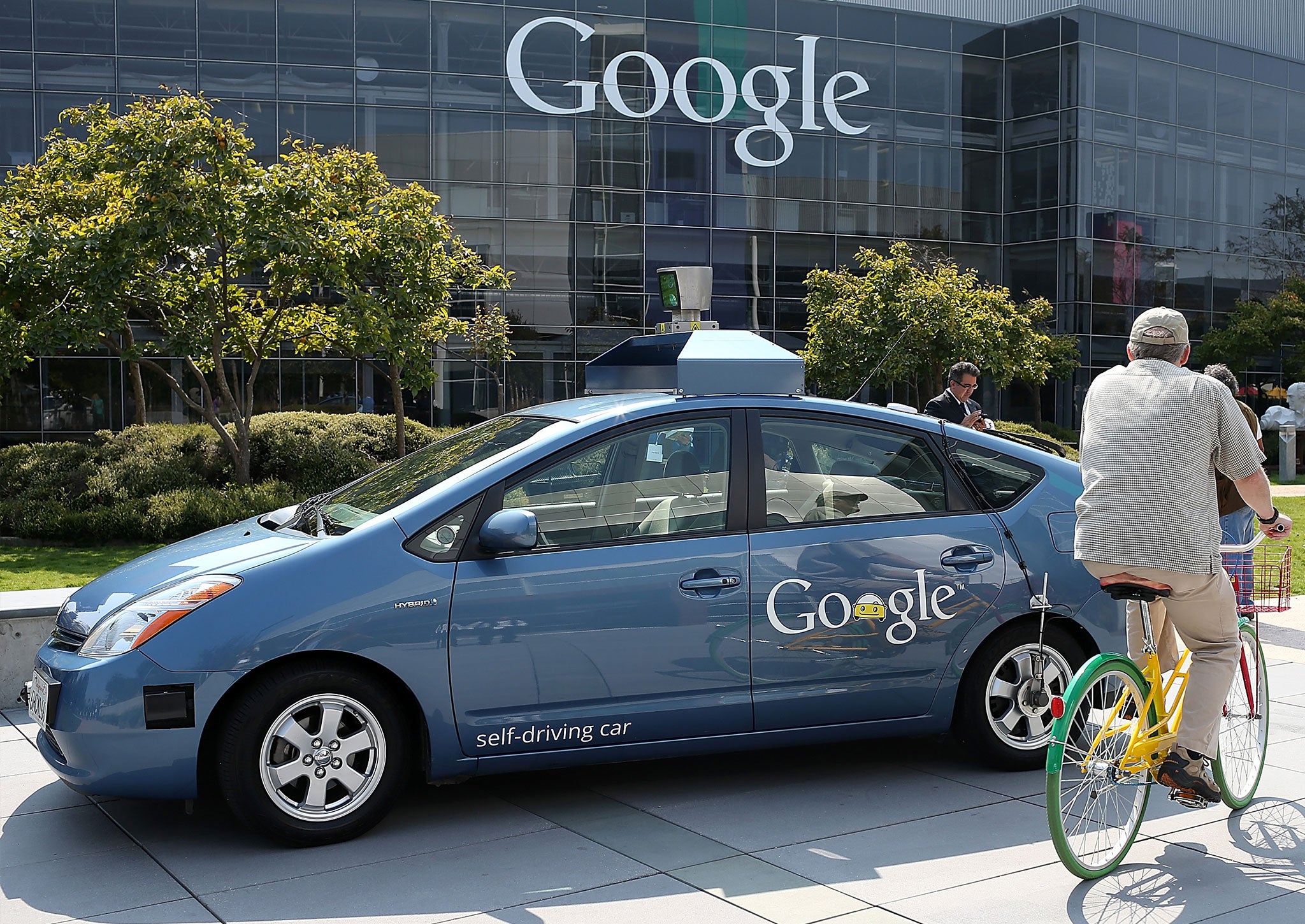 A cyclist rides by a Google self-driving car at the Google headquarters