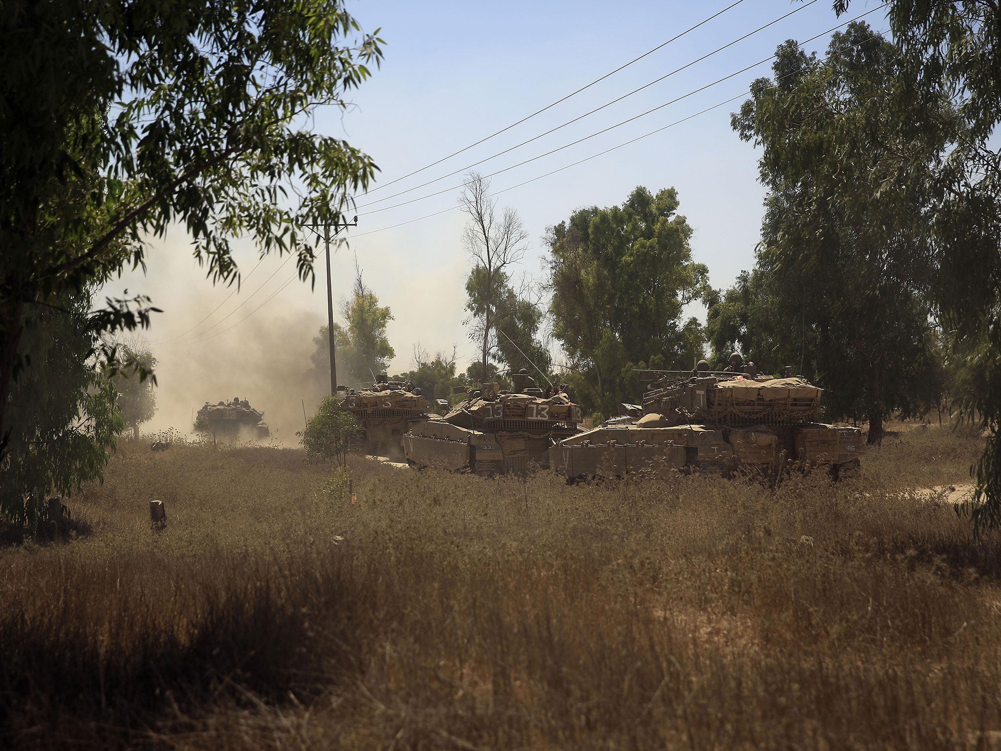 Israeli Merkava tanks drive through trees in southern Israel as they advance towards the Israel Gaza border