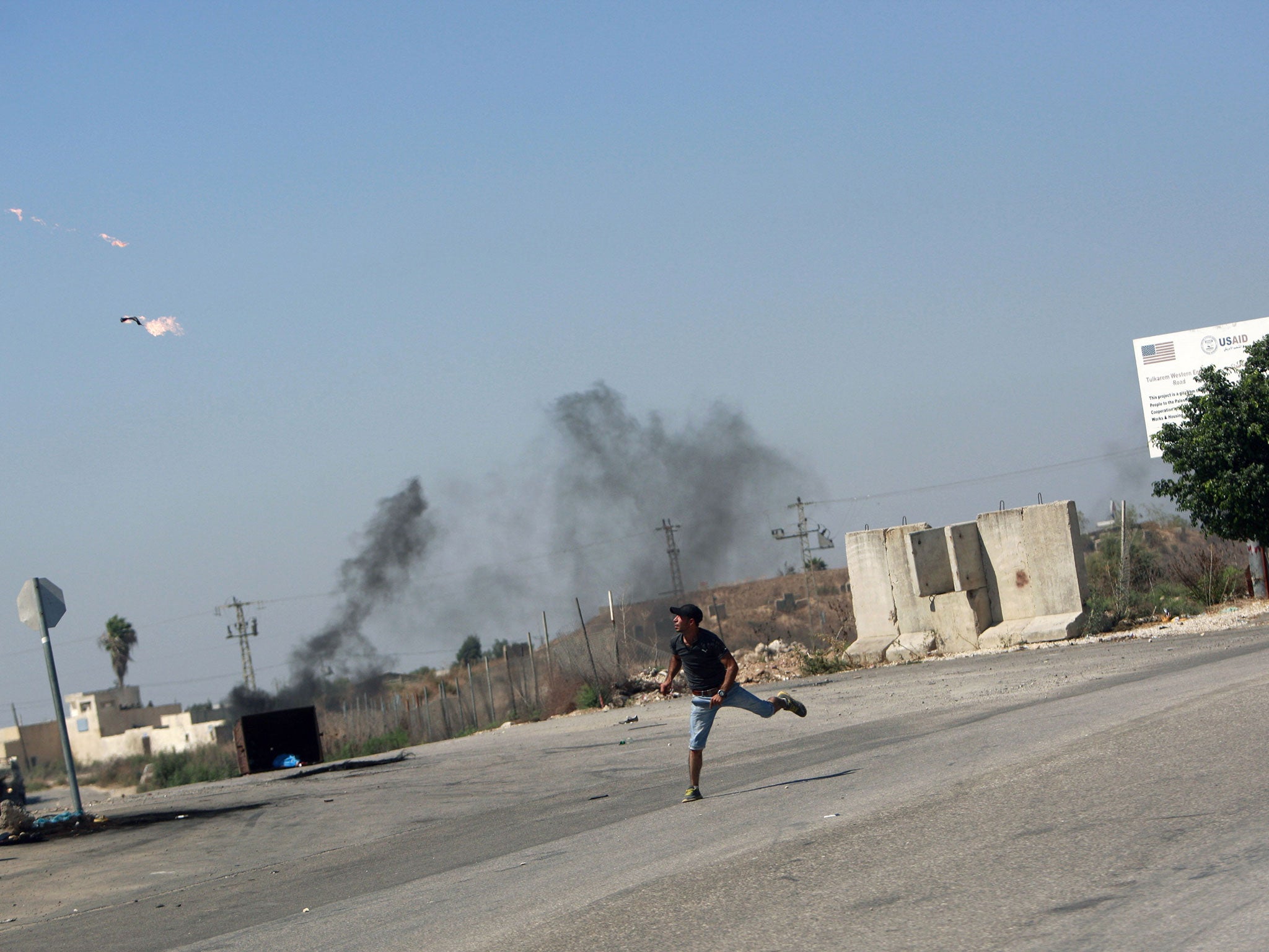 A Palestinian protester throws a Molotov cocktail towards Israeli troops