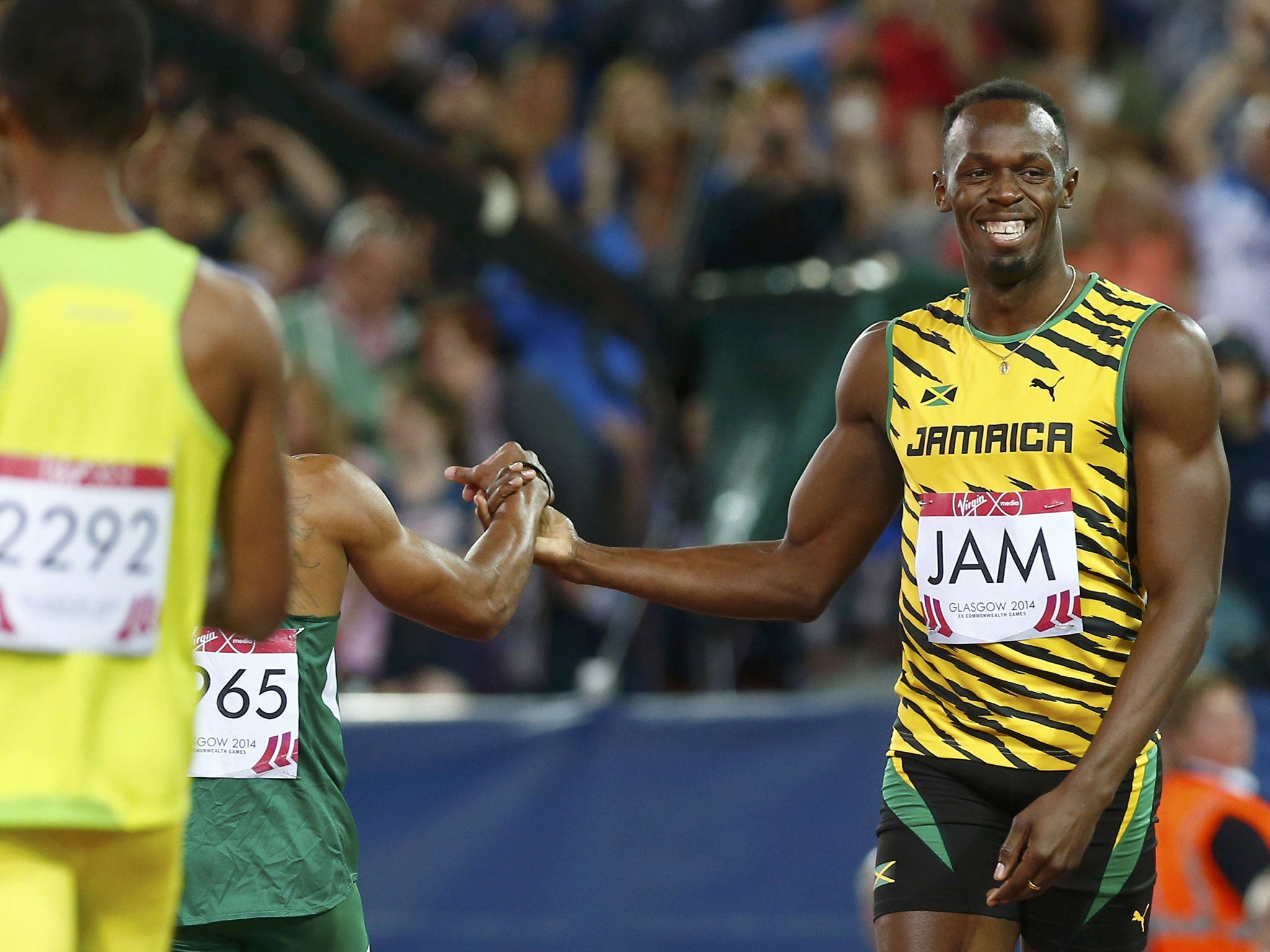 Usain Bolt of Jamaica smiles and shakes hands with a competitor after Jamaica won their first heat in the men's 4x100m relay