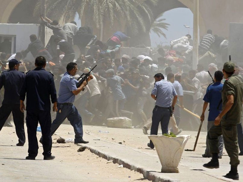 Tunisian guards chase a group of Egyptians trying to storm across the border with Libya at the border crossing of Ras Jdir , southeast of Tunis, on 1 August.