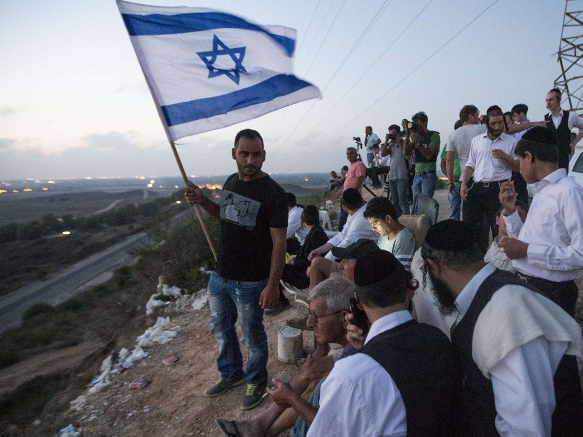 Top down: Israelis, on a hill overlooking Gaza, watch the fighting
