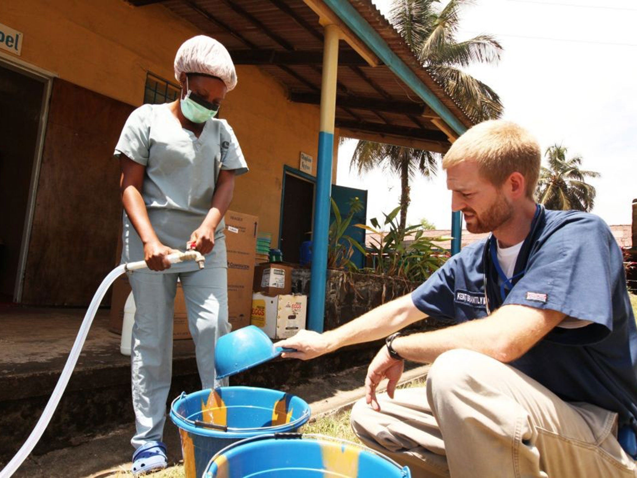 An aid worker helps with the measuring out the disinfectant