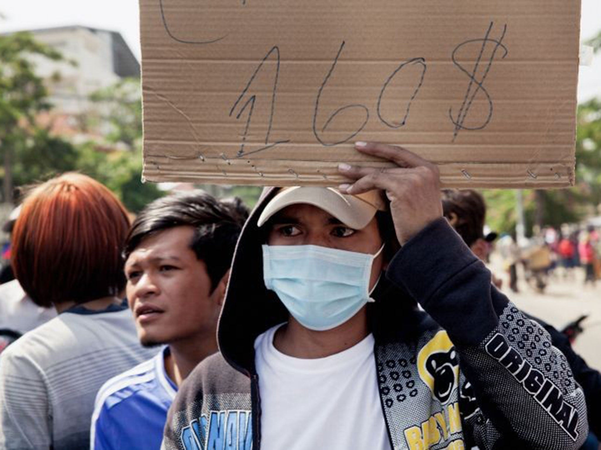 Cost of living; A garment worker on strike holds up a banner demanding a minimum monthly salary of $160 (£95) last December in Phnom Penh, Cambodia