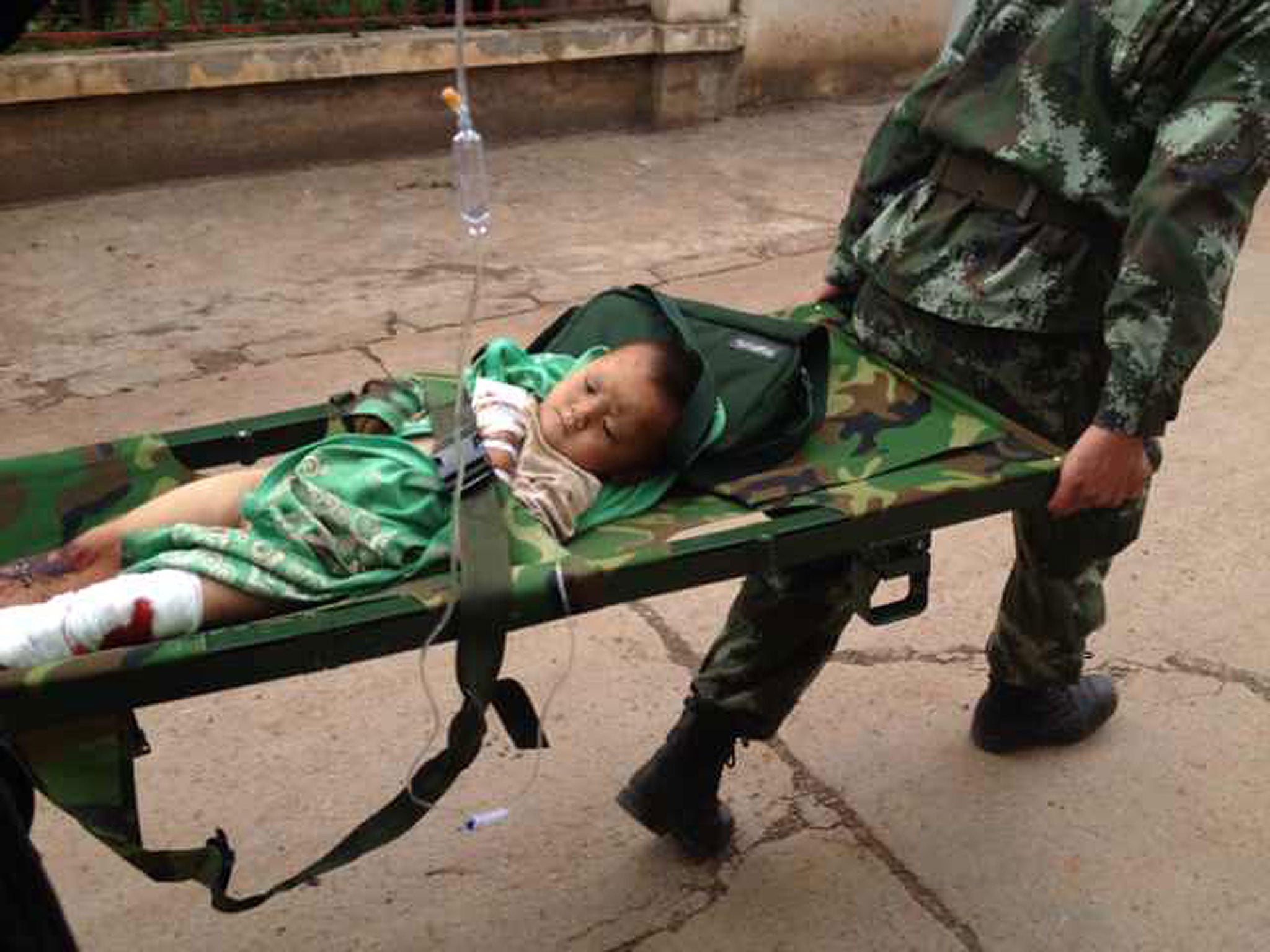 Rescuers carry an injuried child on a stretcher after a 6.1 magnitude earthquake hit the area in Ludian county