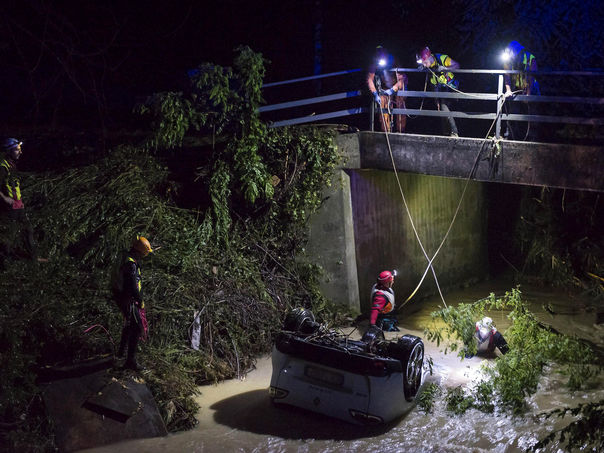 Rescuers search for a missing person inside a car swept away by a torrent near Treviso, northern Italy