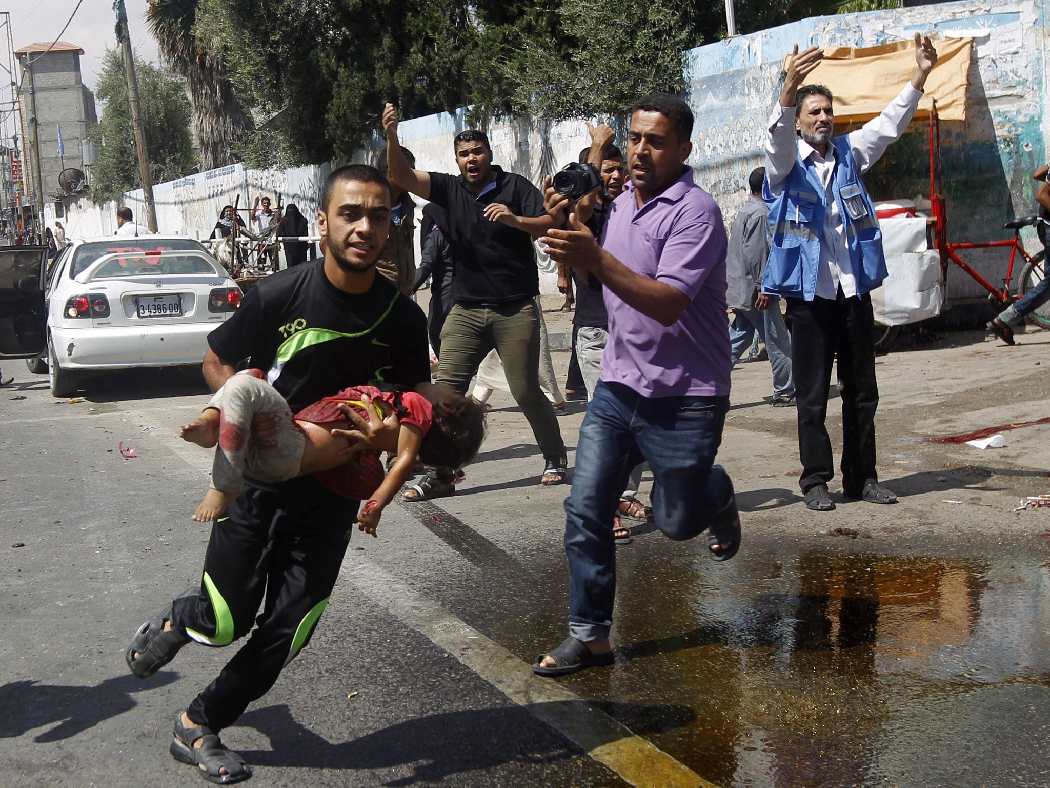 A Palestinian man carries an injured child following the Israeli military strike on the UN shelter in Rafah