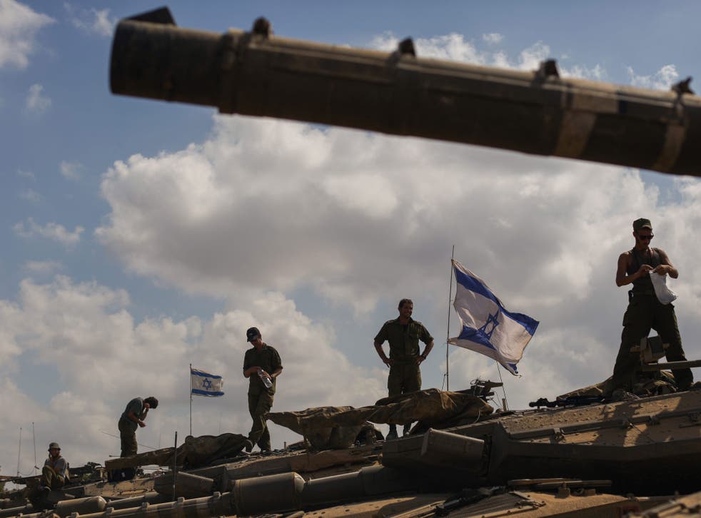 Troops stand on their tanks on the Israeli border after being withdrawn from the Gaza Strip but there has been no order to end the operation