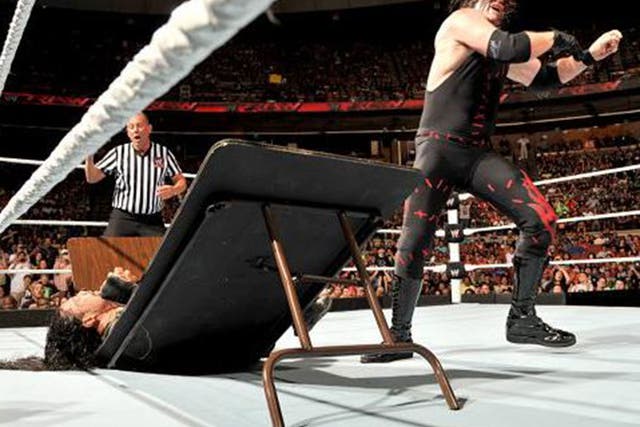 Kane slams Roman Reigns through a table - but he recovered to eventually win the Last Man Standing match