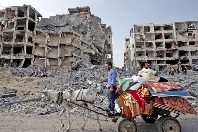 Palestinian men ride a donkey cart past destroyed buildings in the northern Gaza Strip 