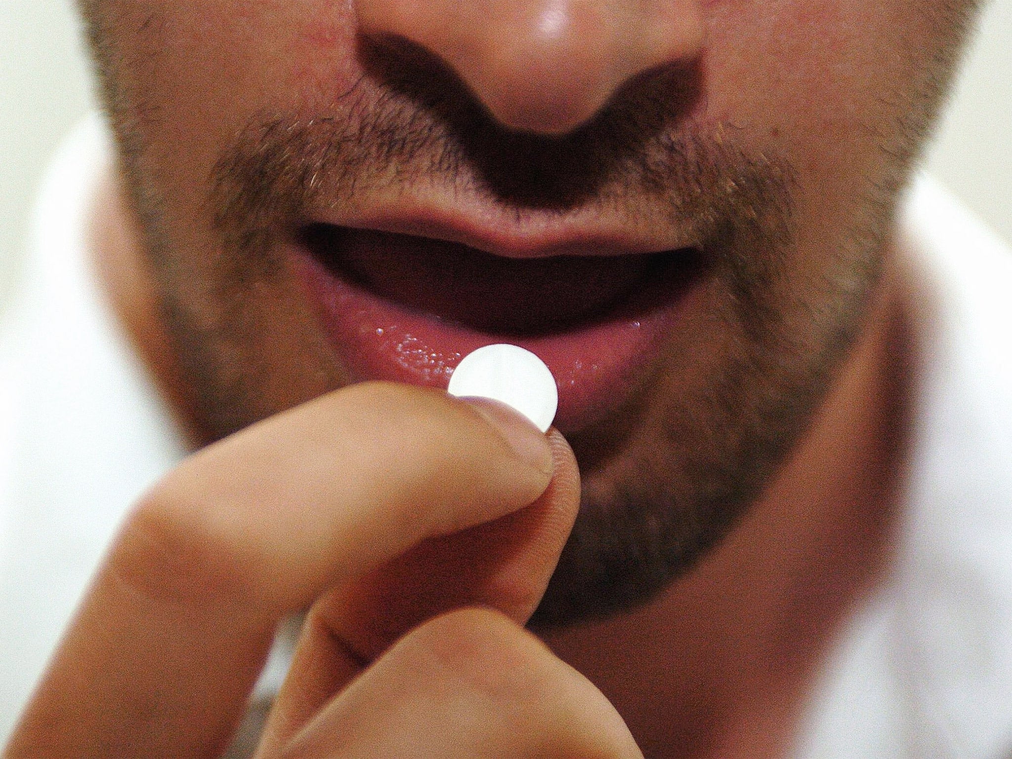 A man taking an Aspirin tablet