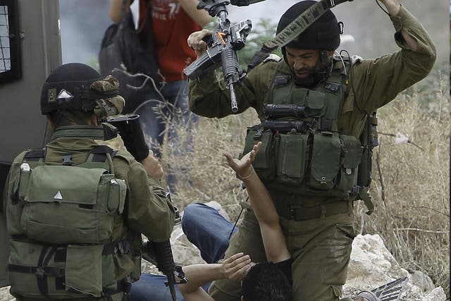 Israeli soldiers detain a Palestinian protester following a demonstration