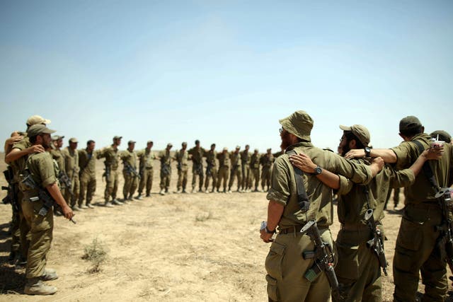Israeli soldiers embrace each other as they sing at a staging area at an unspecified location near the Gaza border