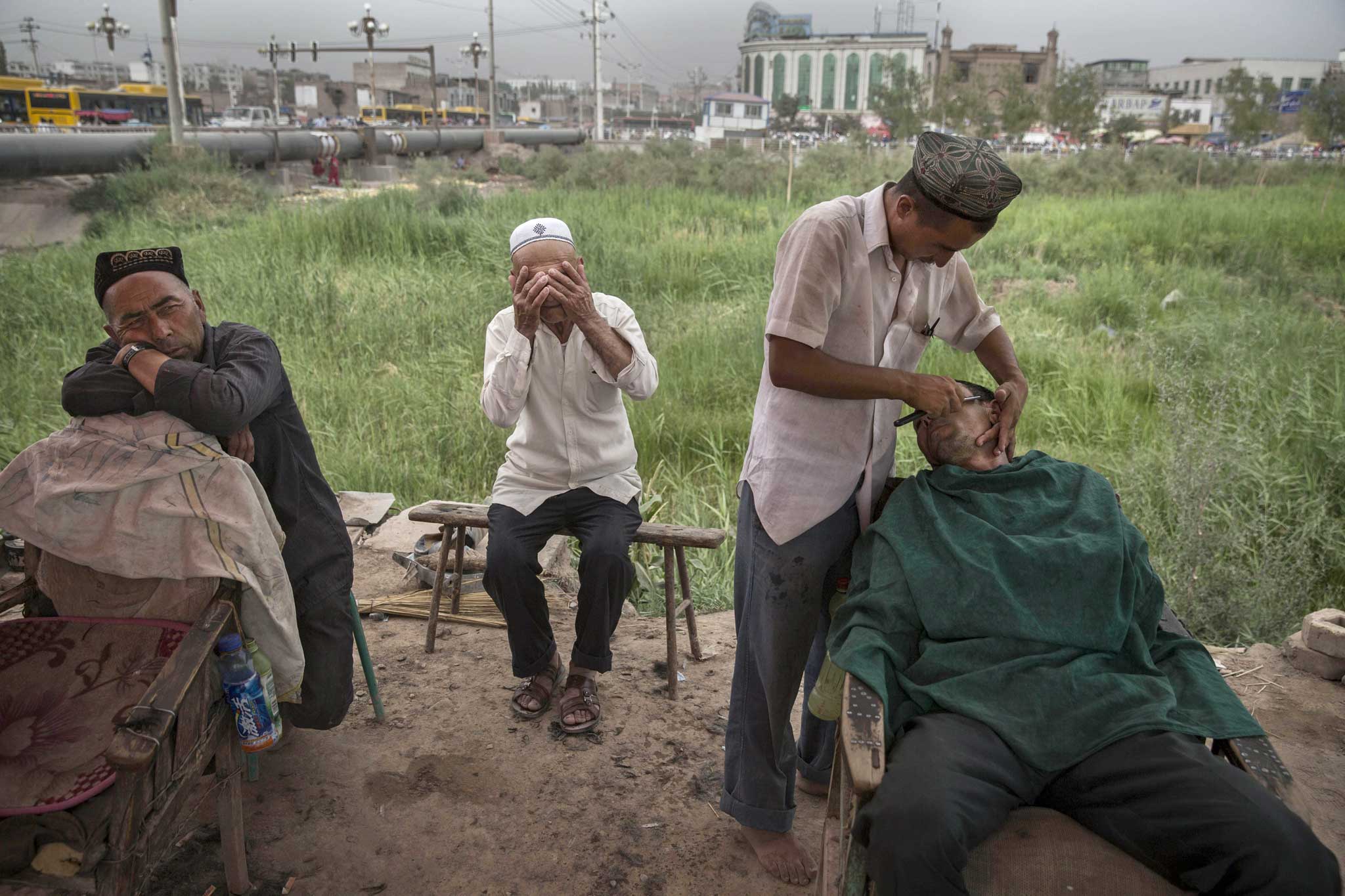 Scraping a living: an Uighur shaves customers at his open air stall in Xinjiang province, the site of recent ethnic unrest