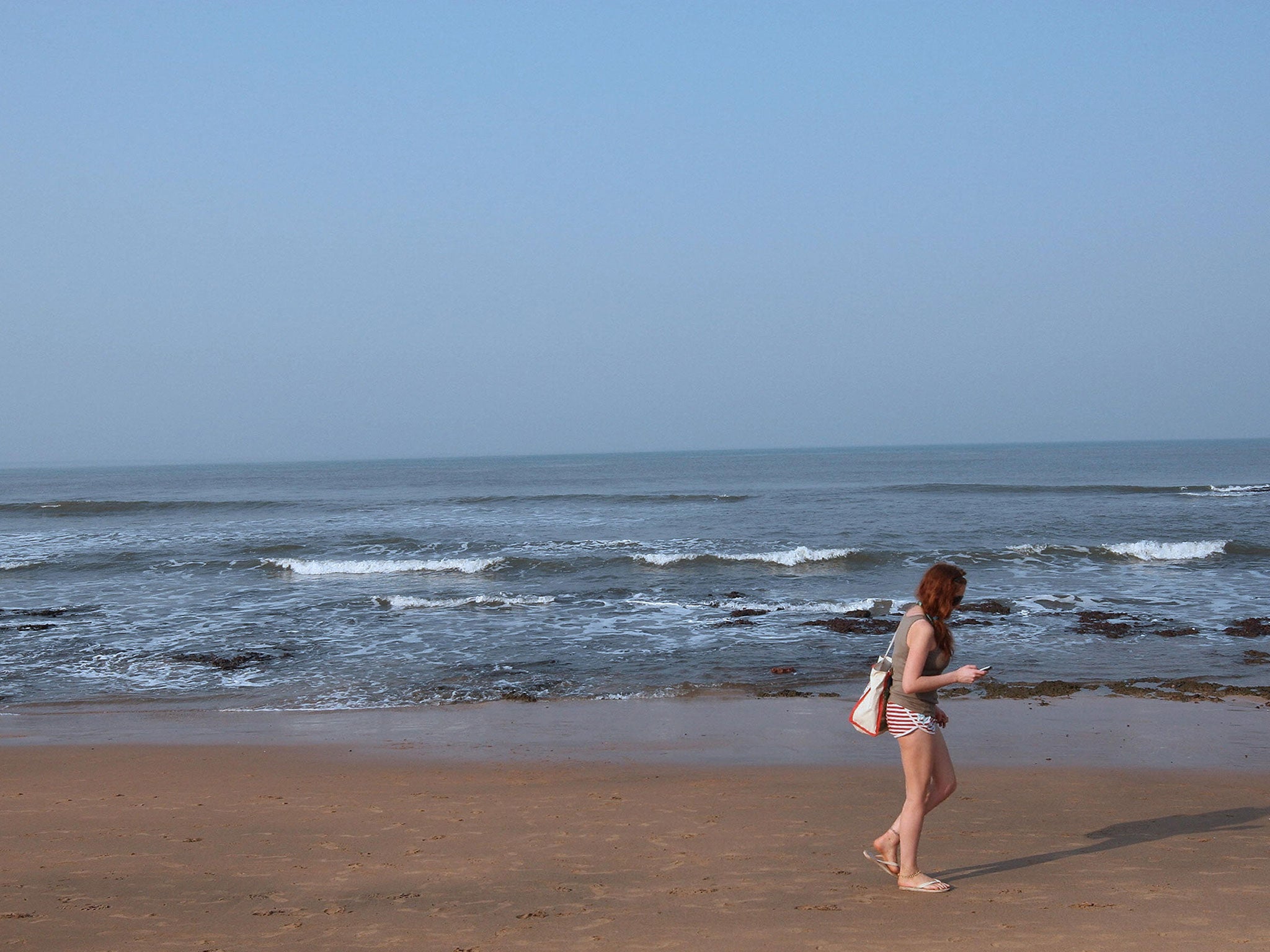 A tourist walks across Anjuna beach in Goa