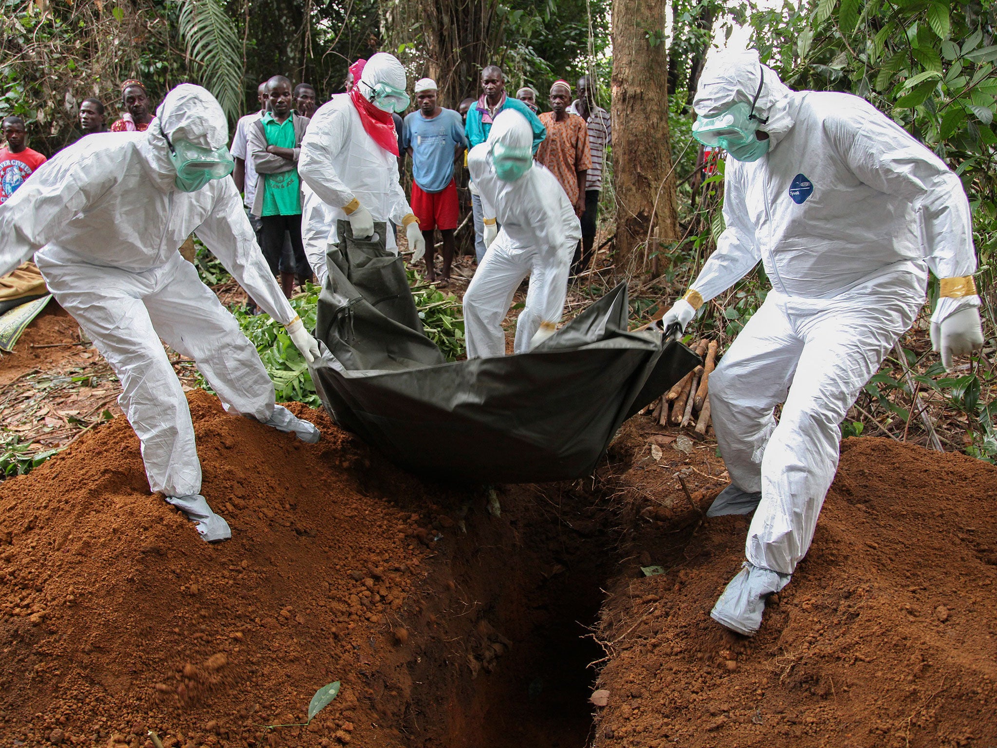 Liberian nurses in protective clothing bury the body of an Ebola victim in the Banjor community on the outskirts of Monrovia, a city in the grip of a real-life nightmare