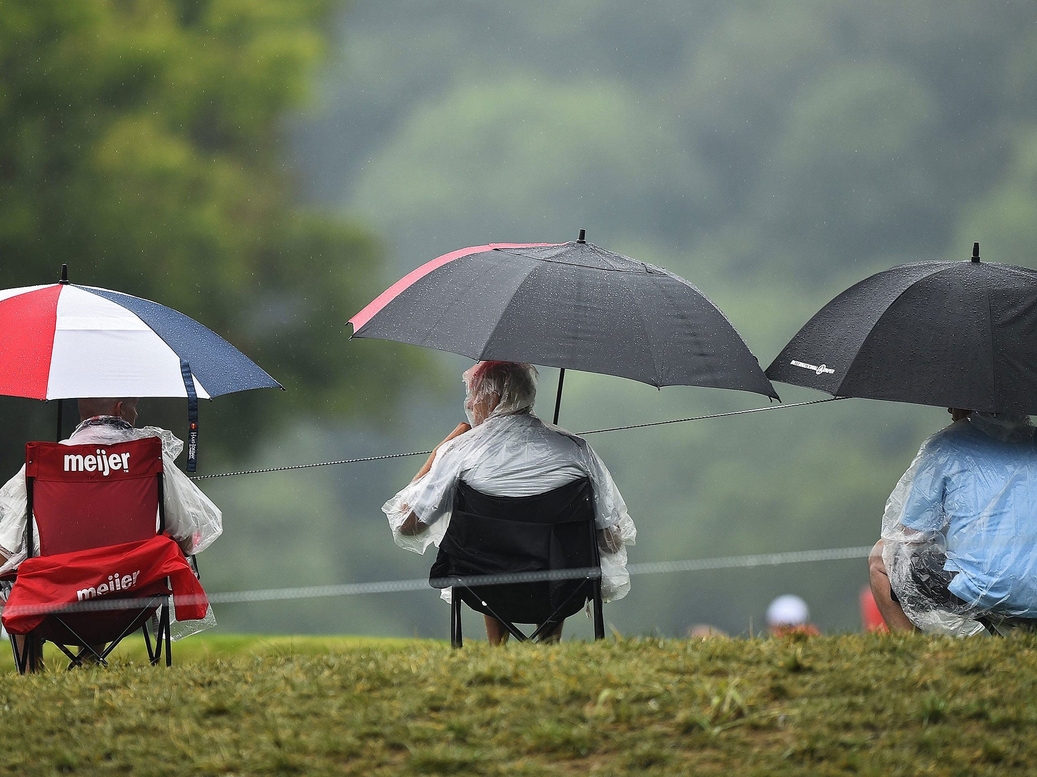Fans wait in the pouring rain for play to start in the morning
