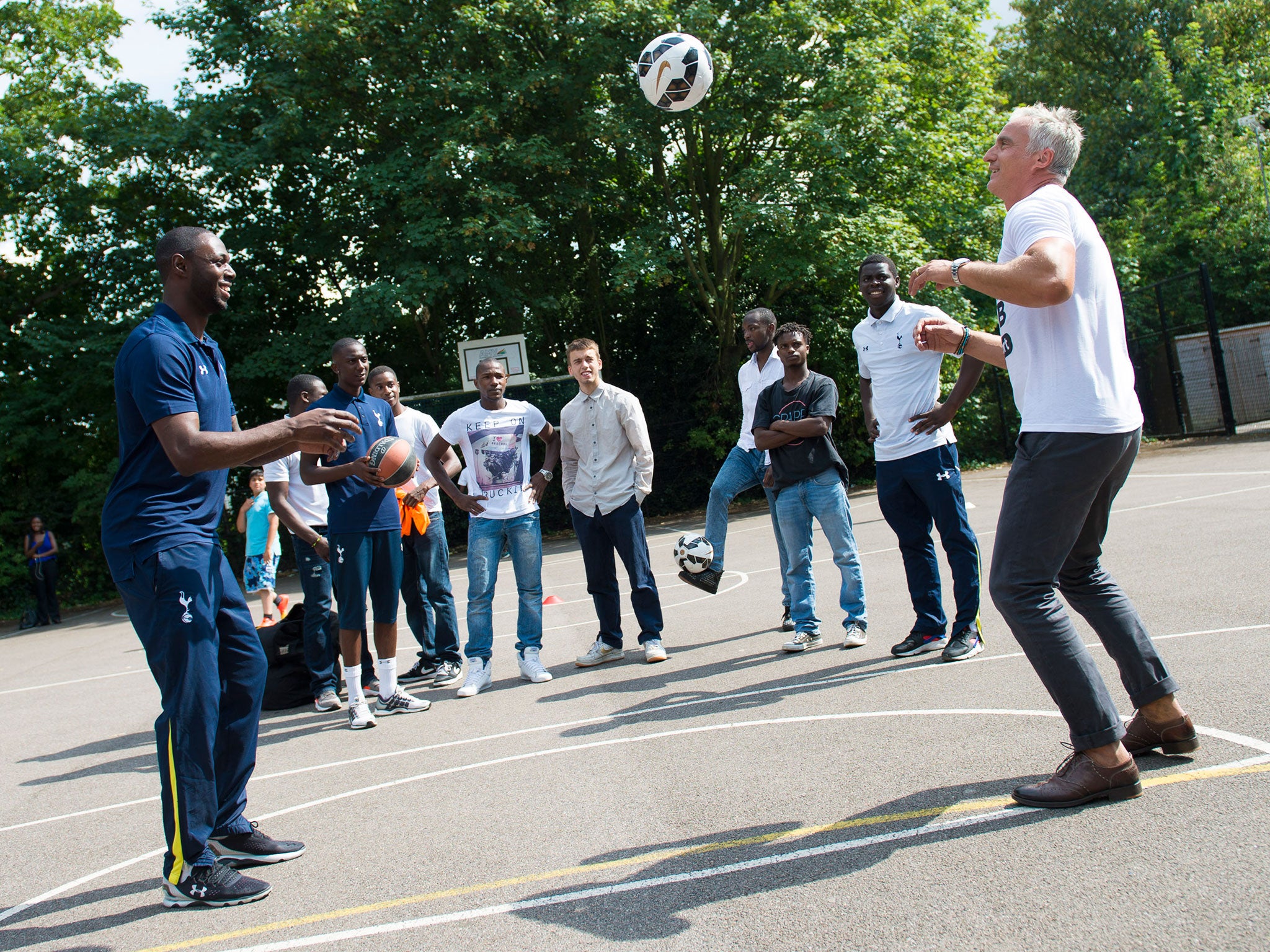Ledley King and David Ginola perform keepy-uppys in front of members of the To Care Is To Do program