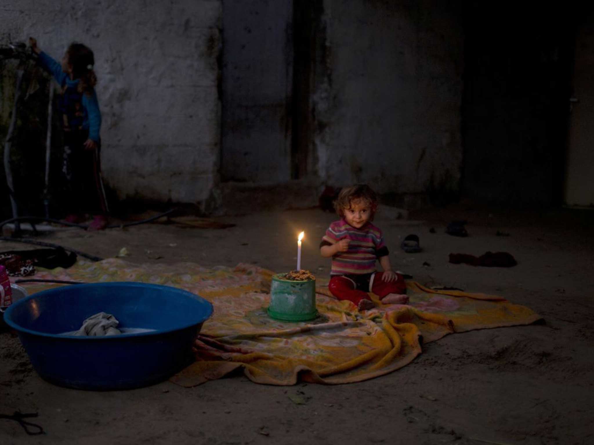 A girl sits beside a flickering candle in Gaza