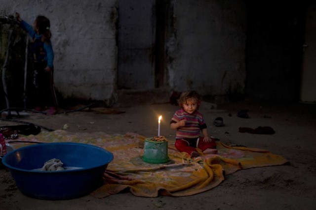 A girl sits beside a flickering candle in Gaza