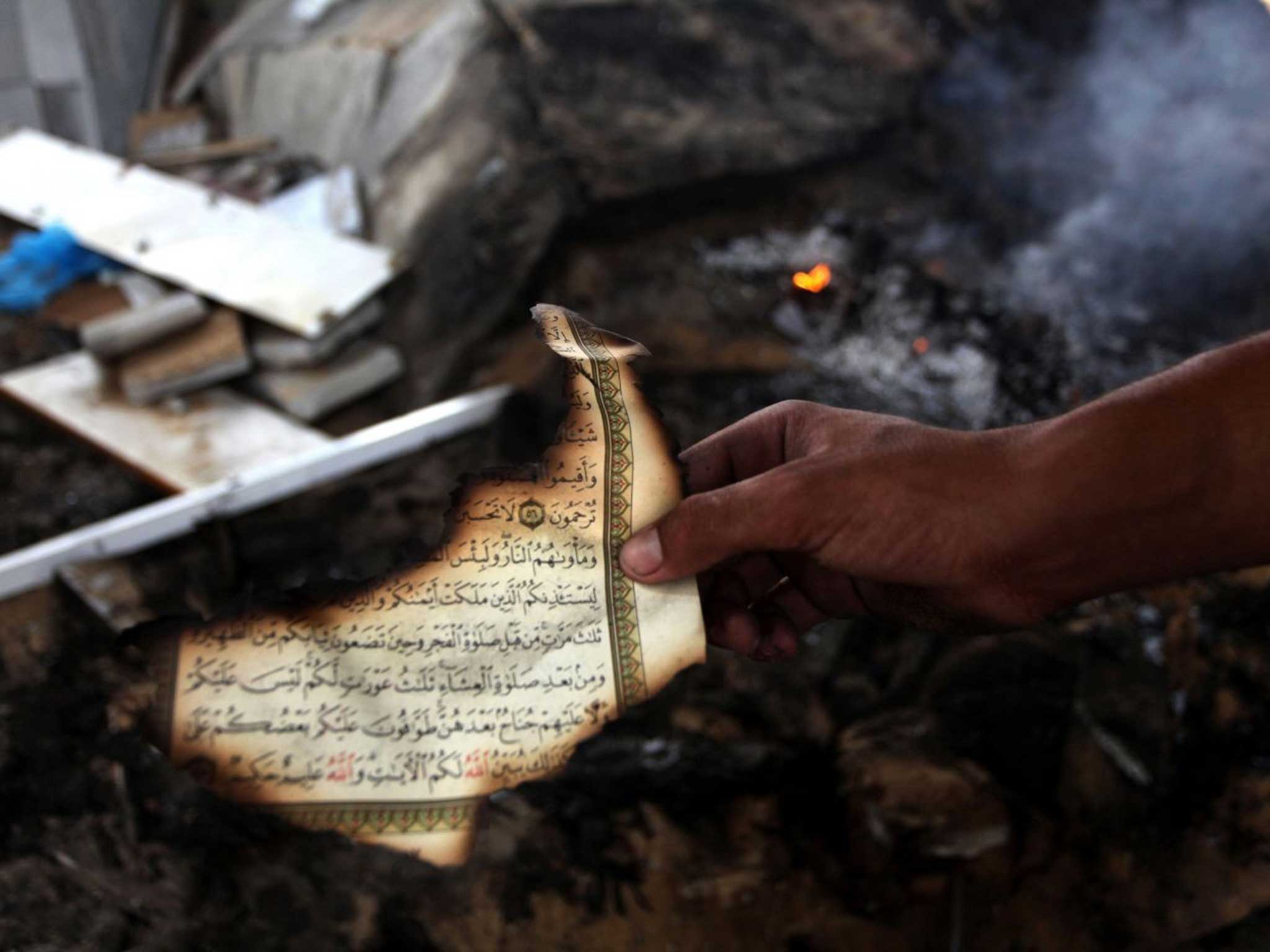 A man holds the remains of a Koran after another mosque was bombed in Gaza