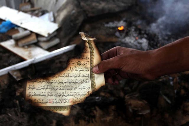 A man holds the remains of a Koran after another mosque was bombed in Gaza