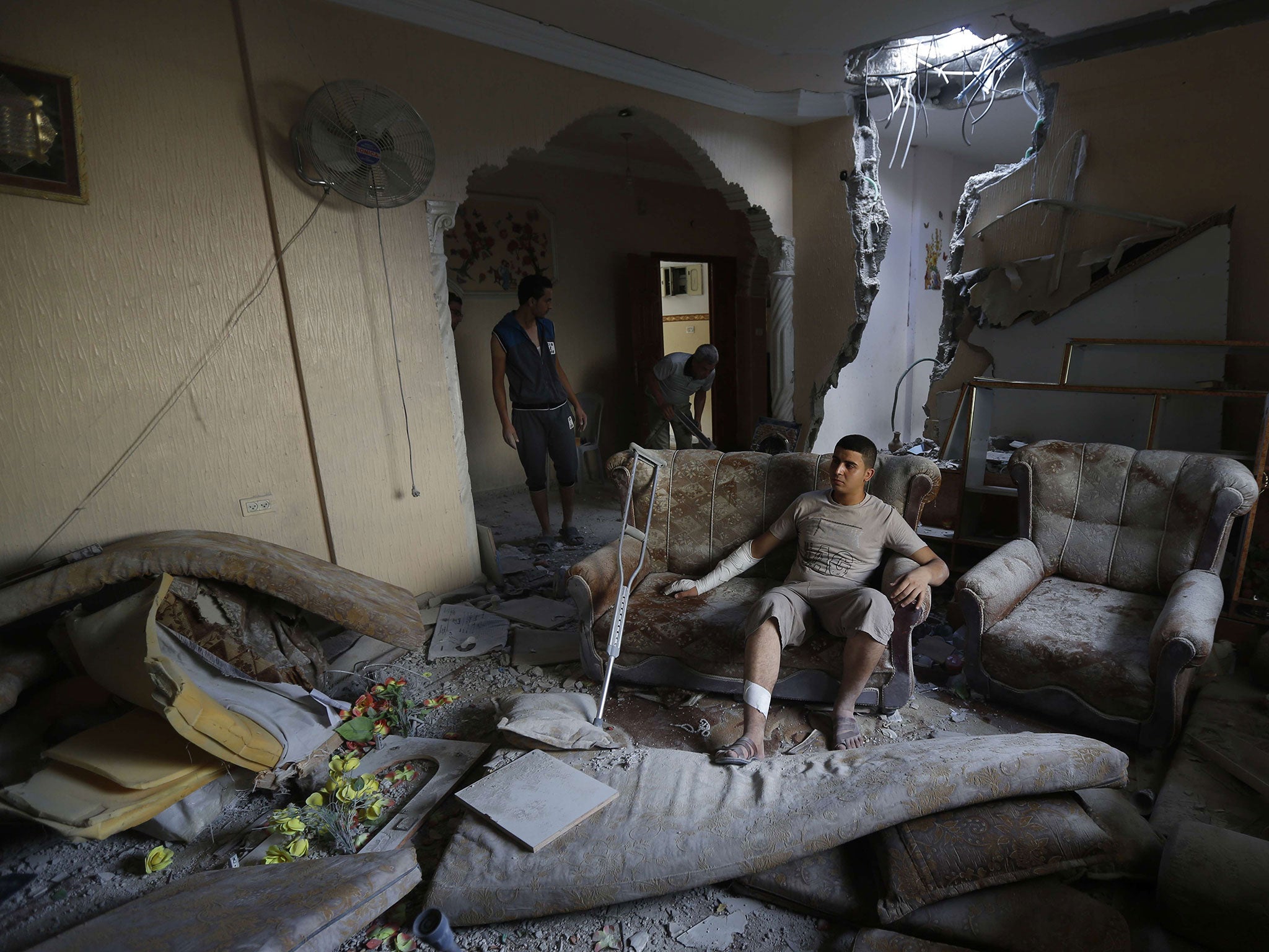 An injured Palestinian sits inside his home yesterday after it was hit by an Israeli military strike on the Jabaliya refugee camp in the northern Gaza Strip