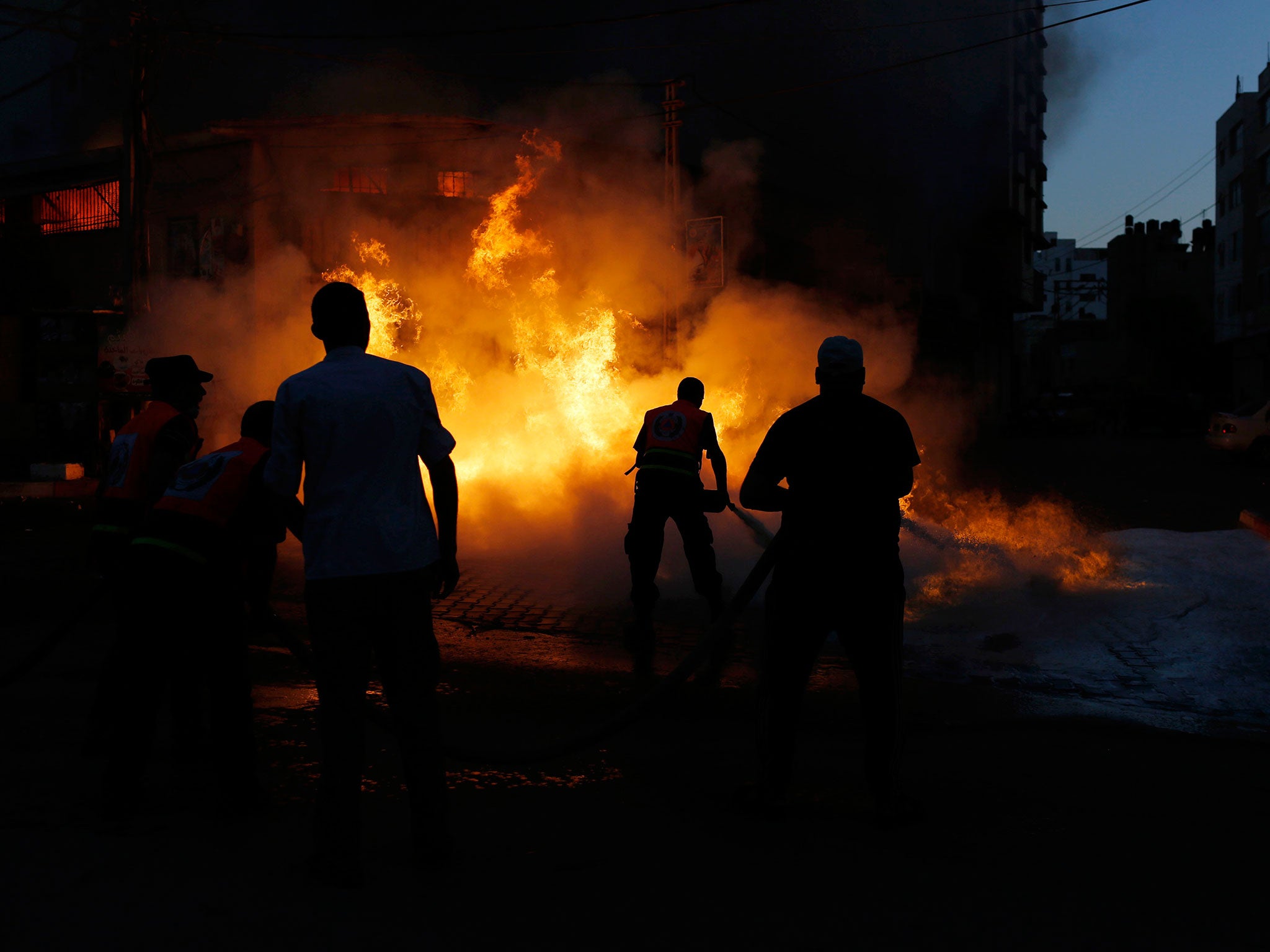 Firefighters try to extinguish a blaze in Gaza City that witnesses claimed was caused by an Israeli air strike