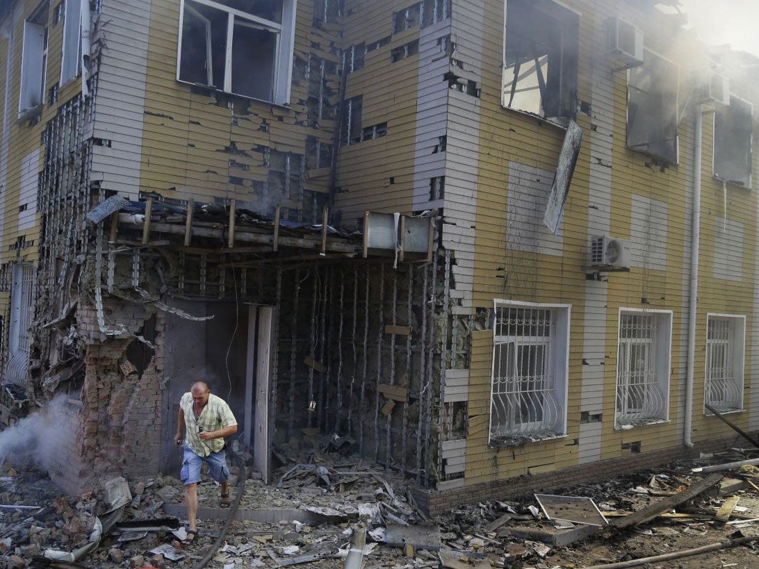 A man runs out of the destroyed building after shelling in Donetsk on 10 August