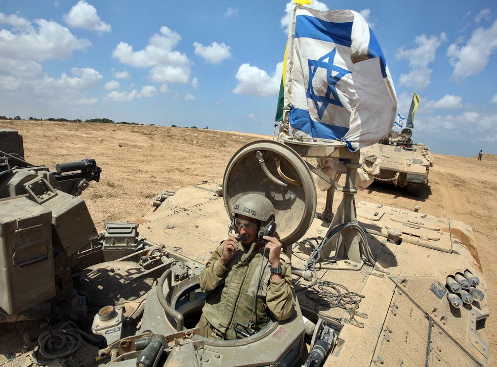 An Israeli soldier sits in an armored personnel carrier (APC) flying the Israeli flag as they return from the border between Israel and the Gaza Strip
