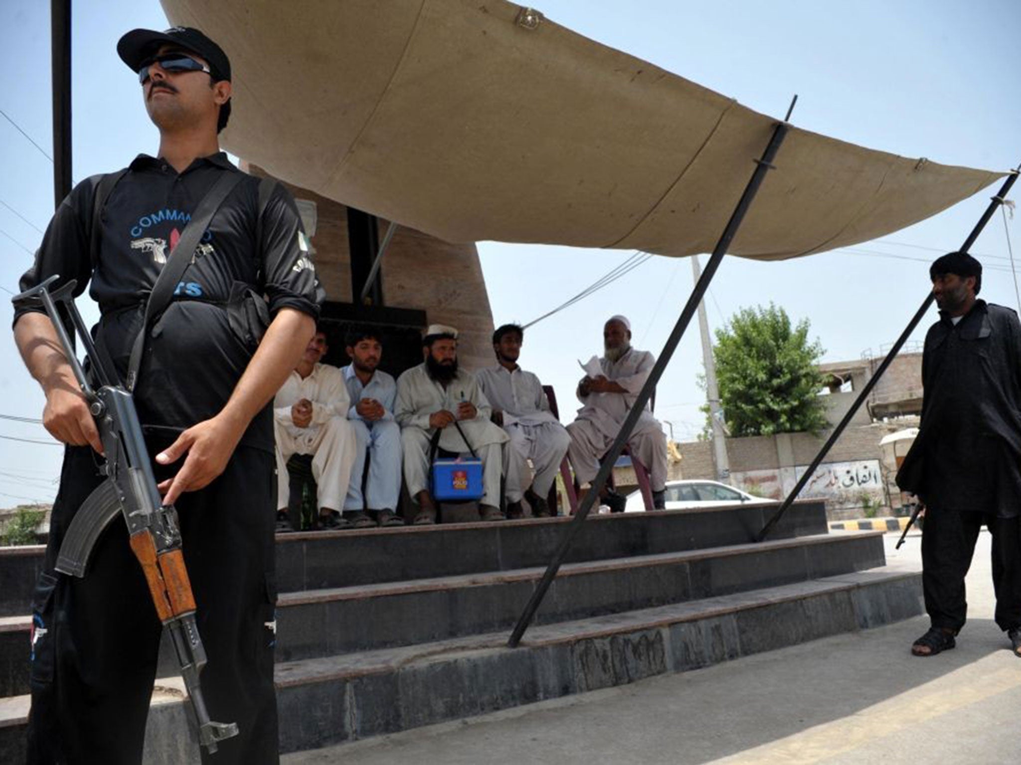 Pakistani police commandos guard a polio vaccination team at a security checkpoint in Bannu