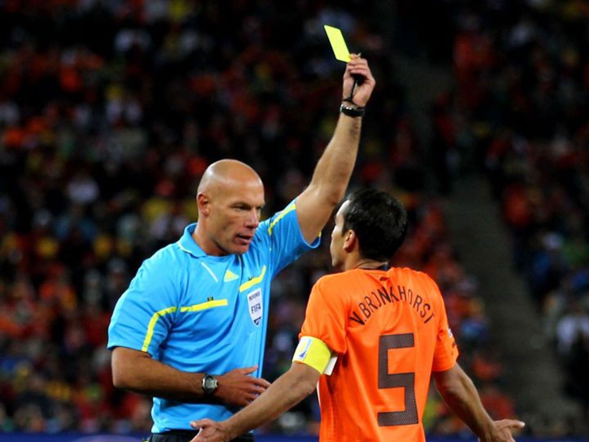 Howard Webb shows a yellow card to Giovanni van Bronckhorst at Soccer City while refereeing the 2010 World Cup final between the Netherlands and Spain