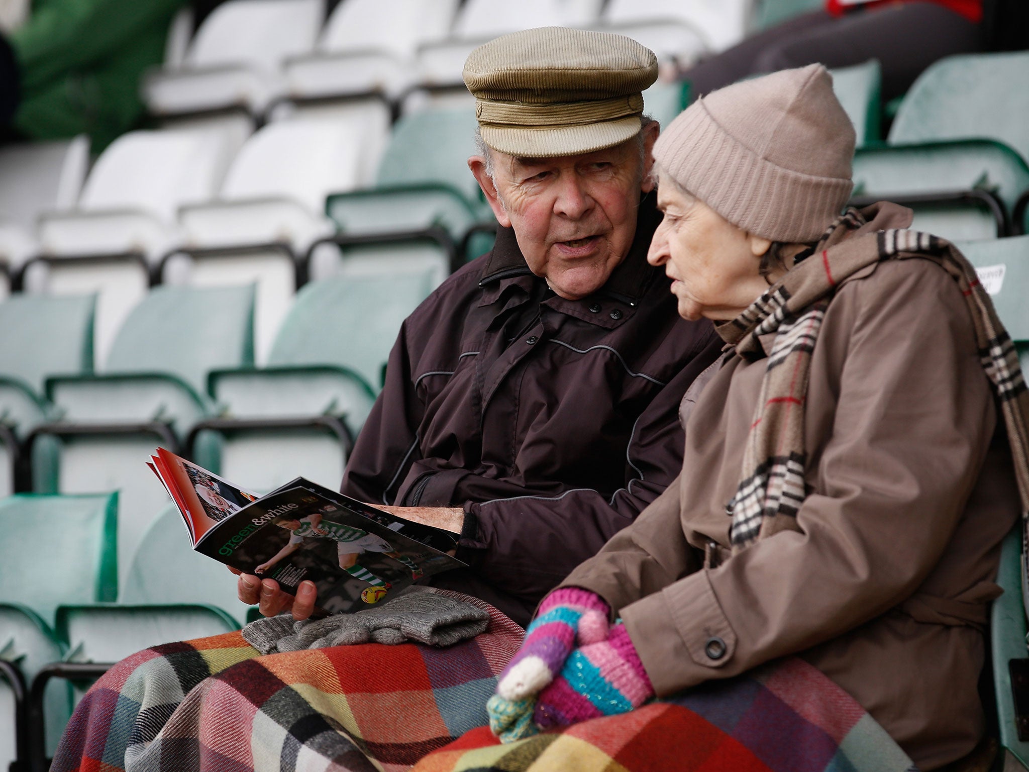 Two elderly spectators at a football match.