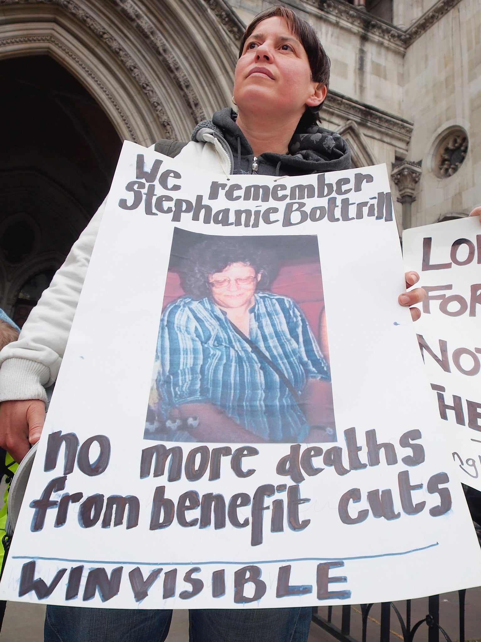 A campaigner at a bedroom tax vigil holds up a placard which reads 'We remember Stephanie Bottrill,' outside the High Court last year