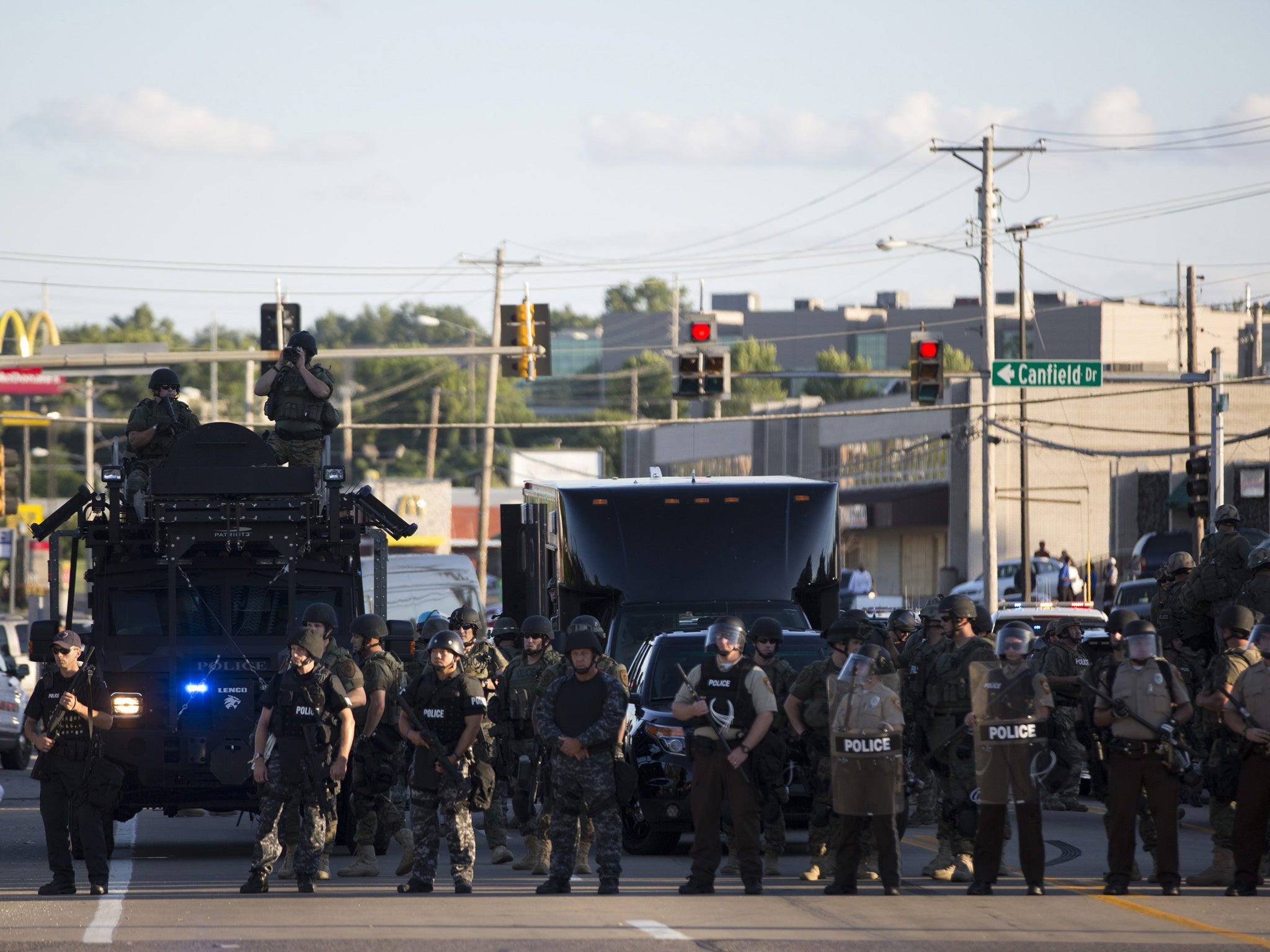Police officers keep watch while demonstrators (not pictured) protest the death of black teenager Michael Brown in Ferguson, Missouri August 12, 2014