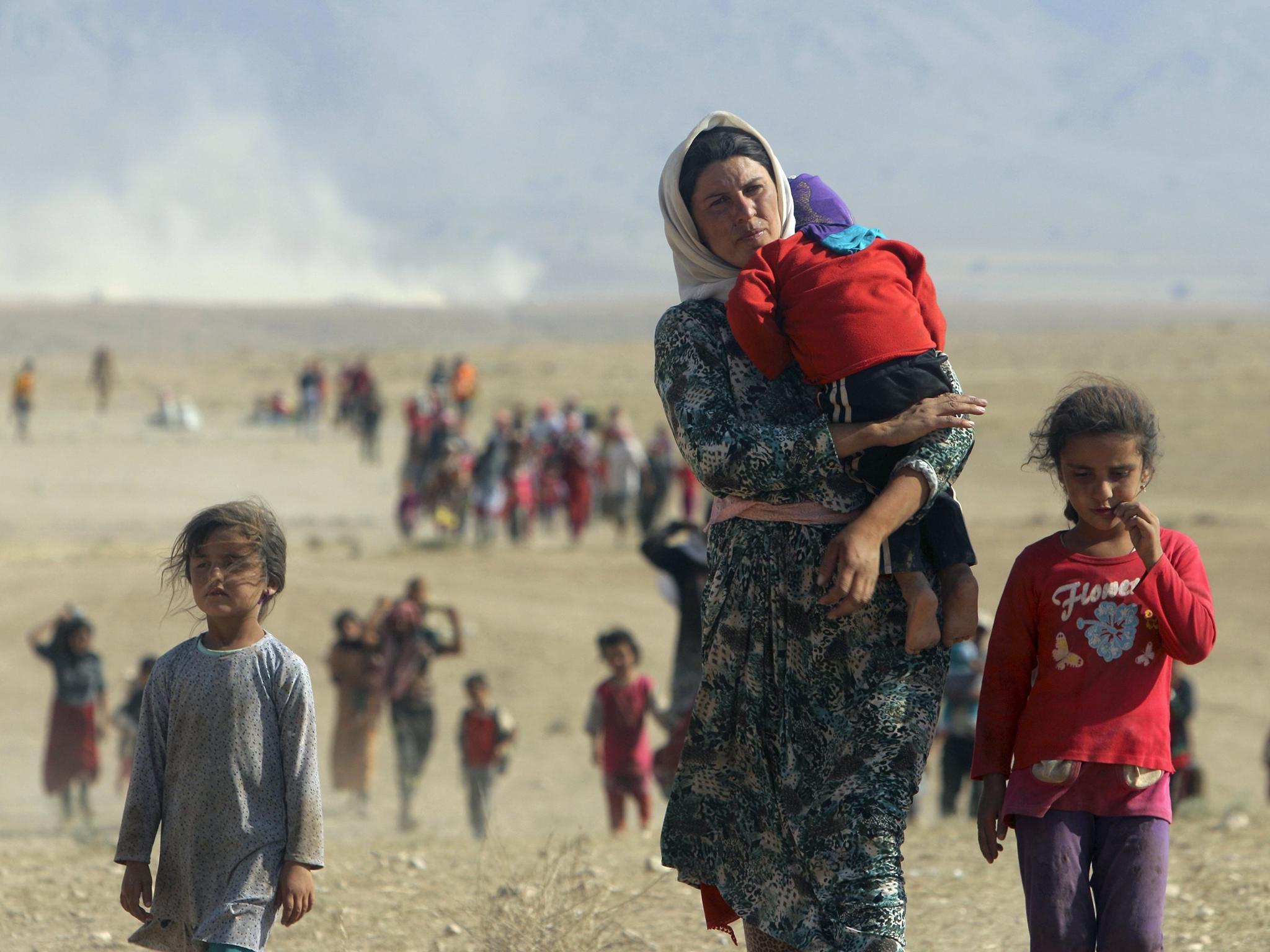 Displaced people from the minority Yazidi sect, fleeing violence from forces loyal to the Isis in Sinjar town, walk towards the Syrian border, on the outskirts of Sinjar mountain, near the Syrian border town of Elierbeh of Al-Hasakah Governorate