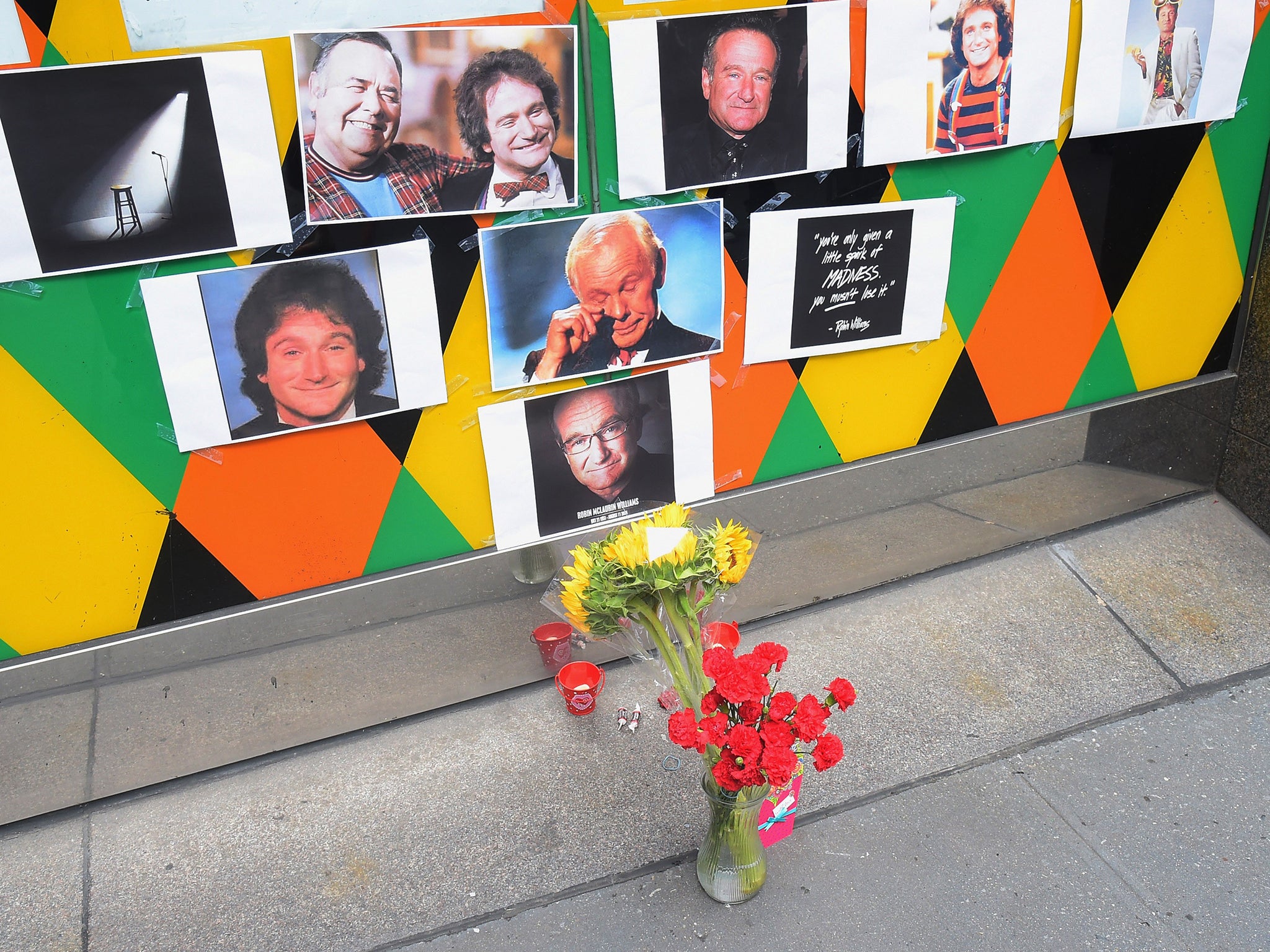 Flowers, tootsie rolls, a card, and a candle are placed in memory of Robin Williams in front of Carolines on Broadway comedy club in New York City