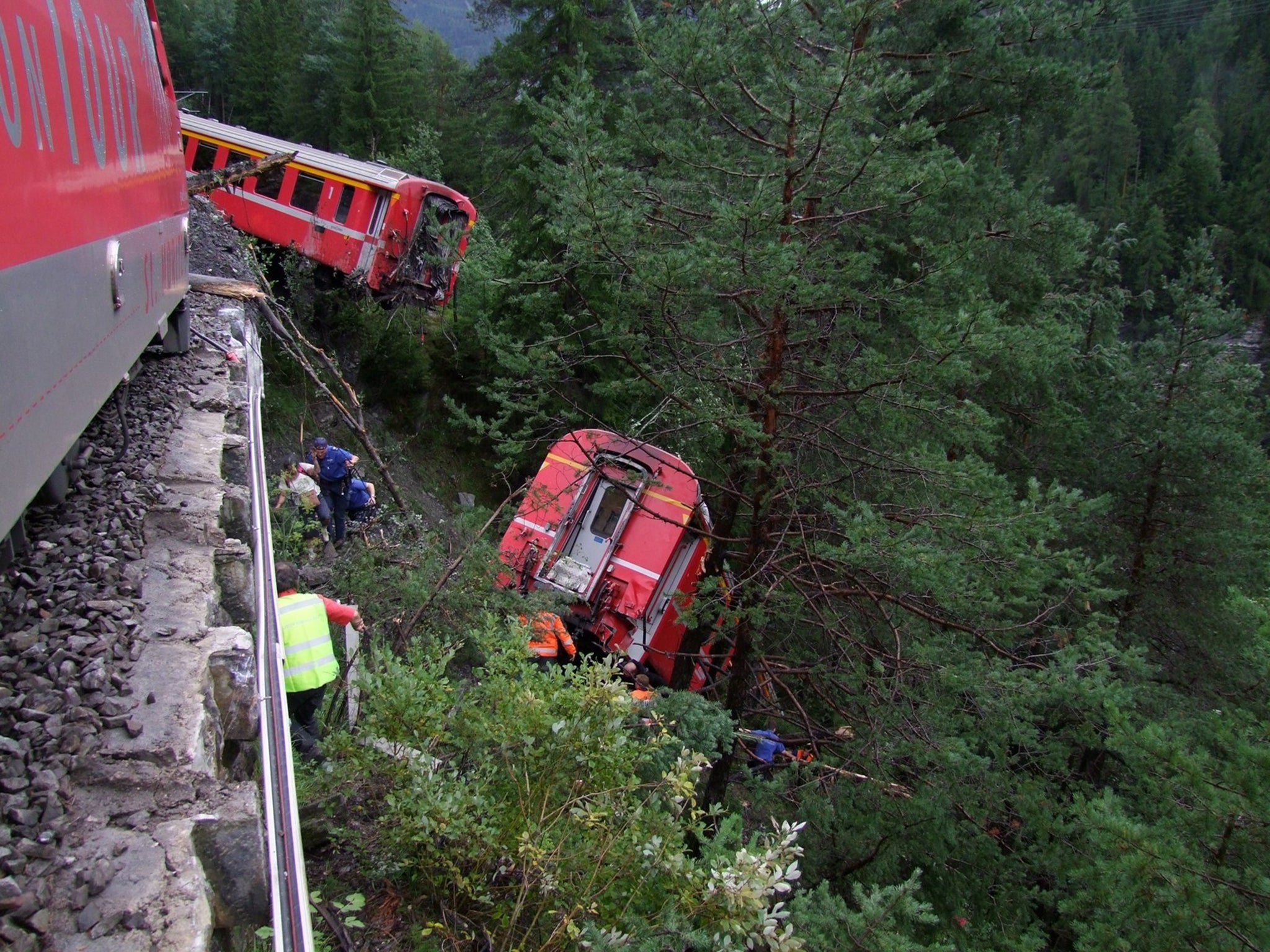 Police and rescue workers help after a passenger train derailed into a ravine near Tiefencastel in a mountainous region of southeastern Switzerland after encountering a mudslide on the tracks
