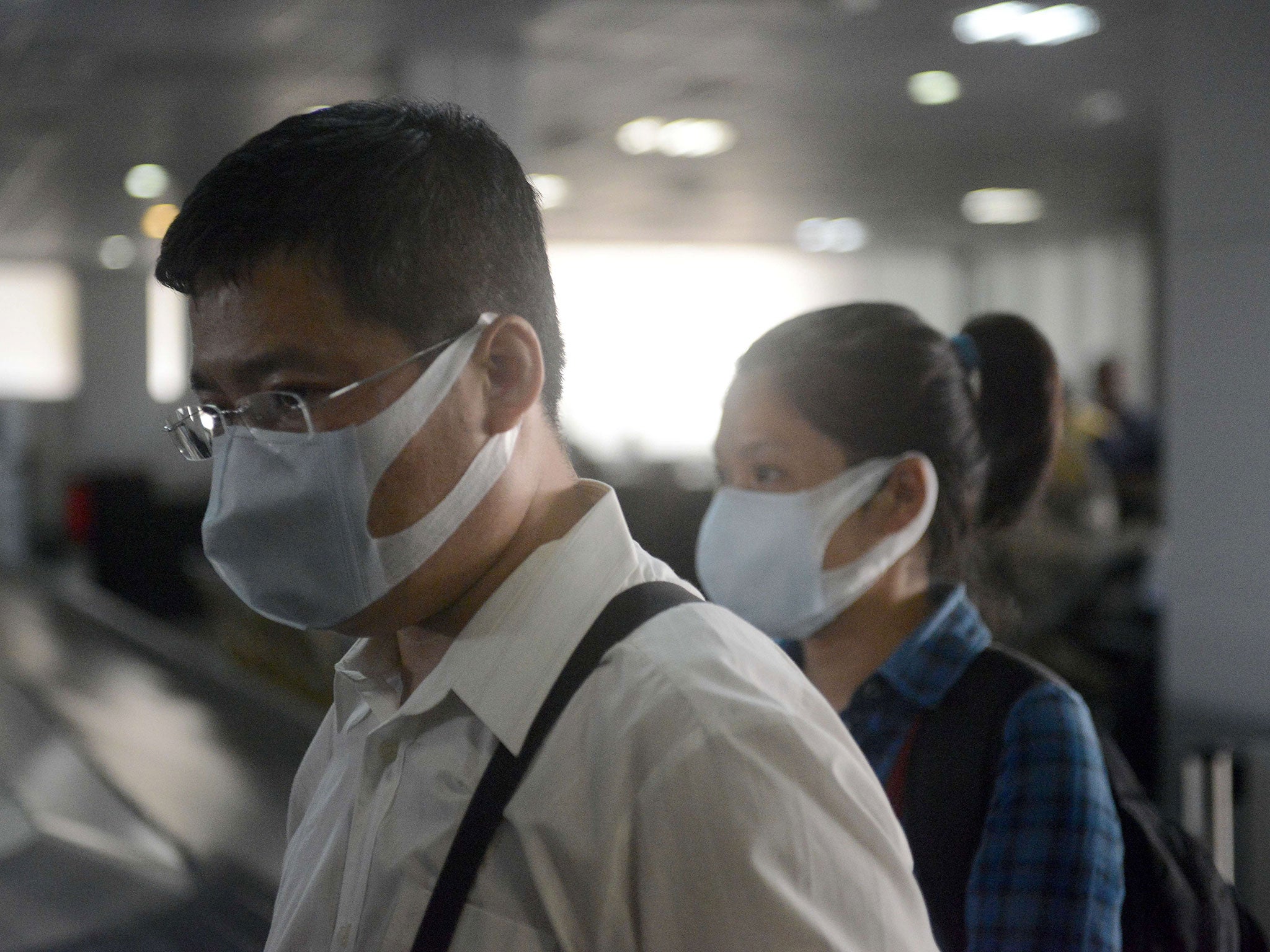 People, wearing protective face masks, stand upon arrival at the Murtala Mohammed Airport in Lagos
