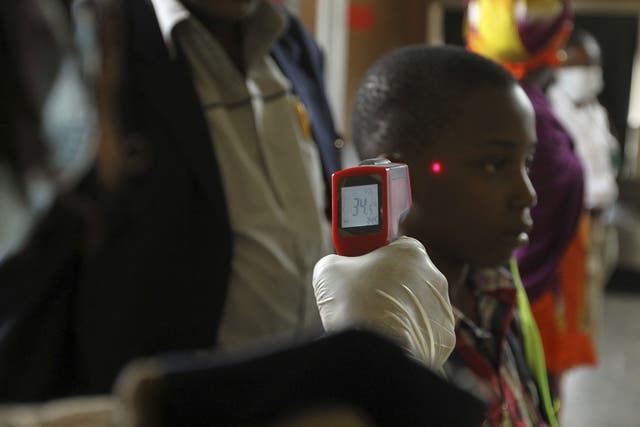 A boy’s temperature is taken using an infrared laser thermometer at the international airport in Abuja, Nigeria